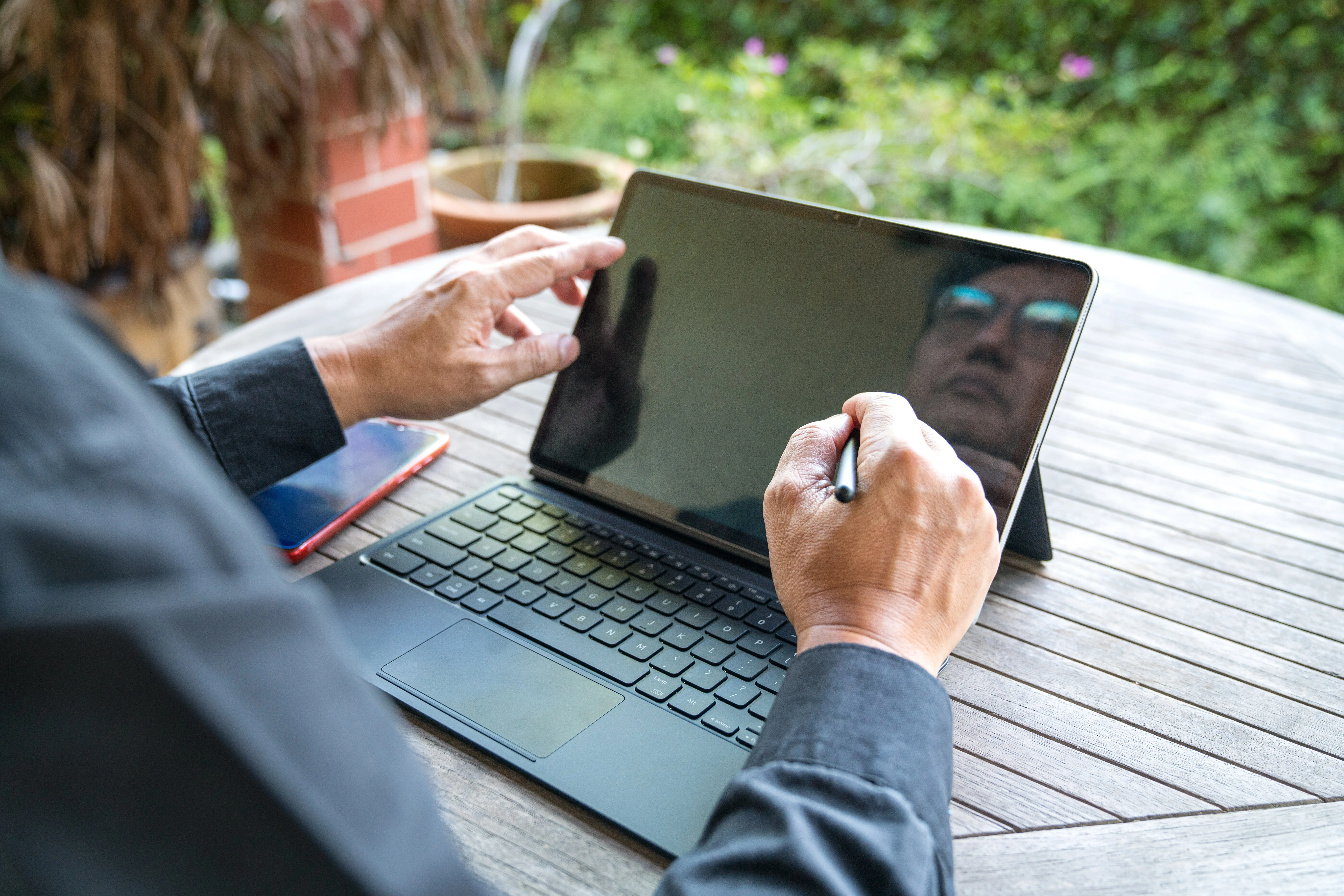 Close-up of a businessman working on his tablet on a patio facing the garden.