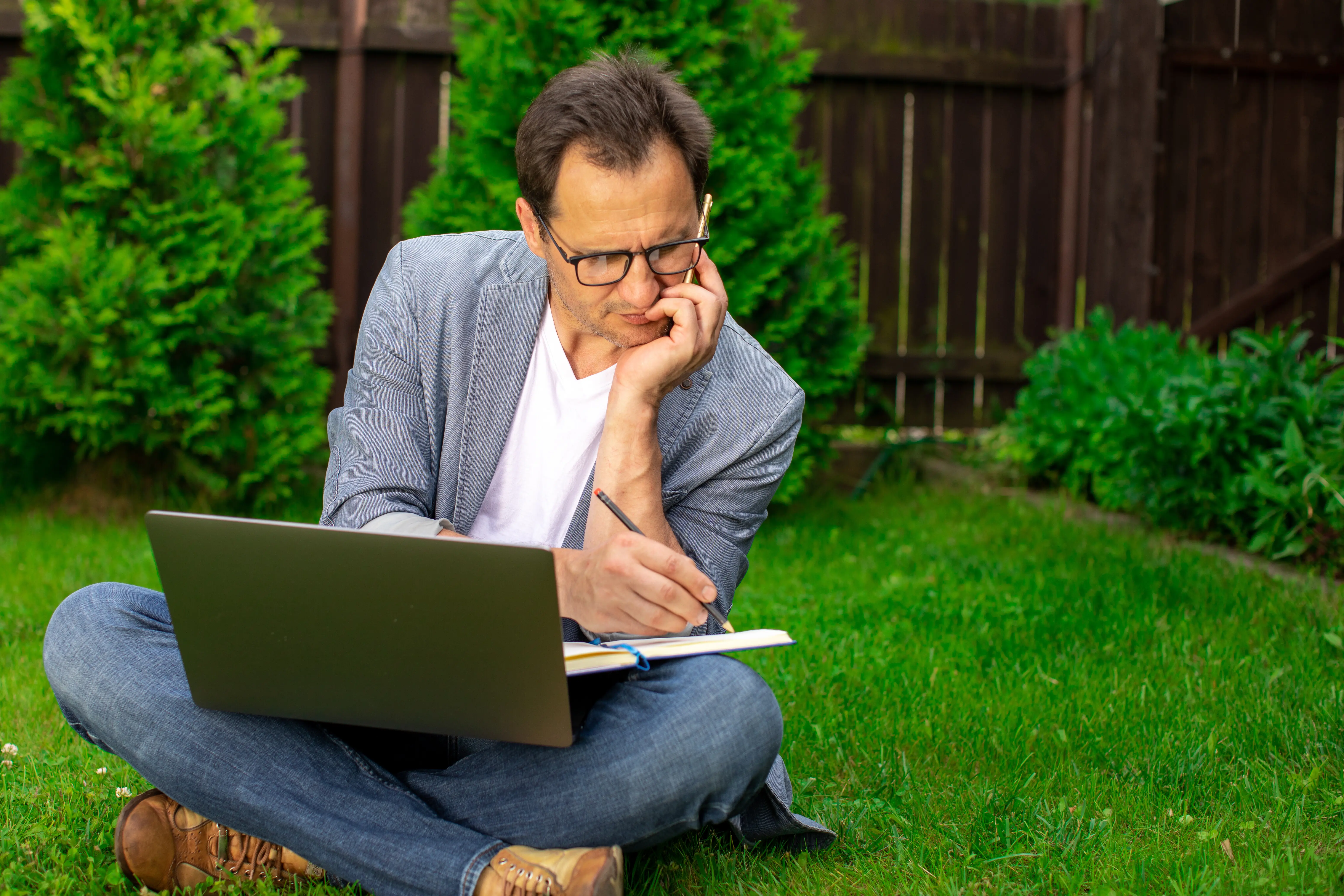 Full-length view of a man using a mobile phone while sitting on grass.